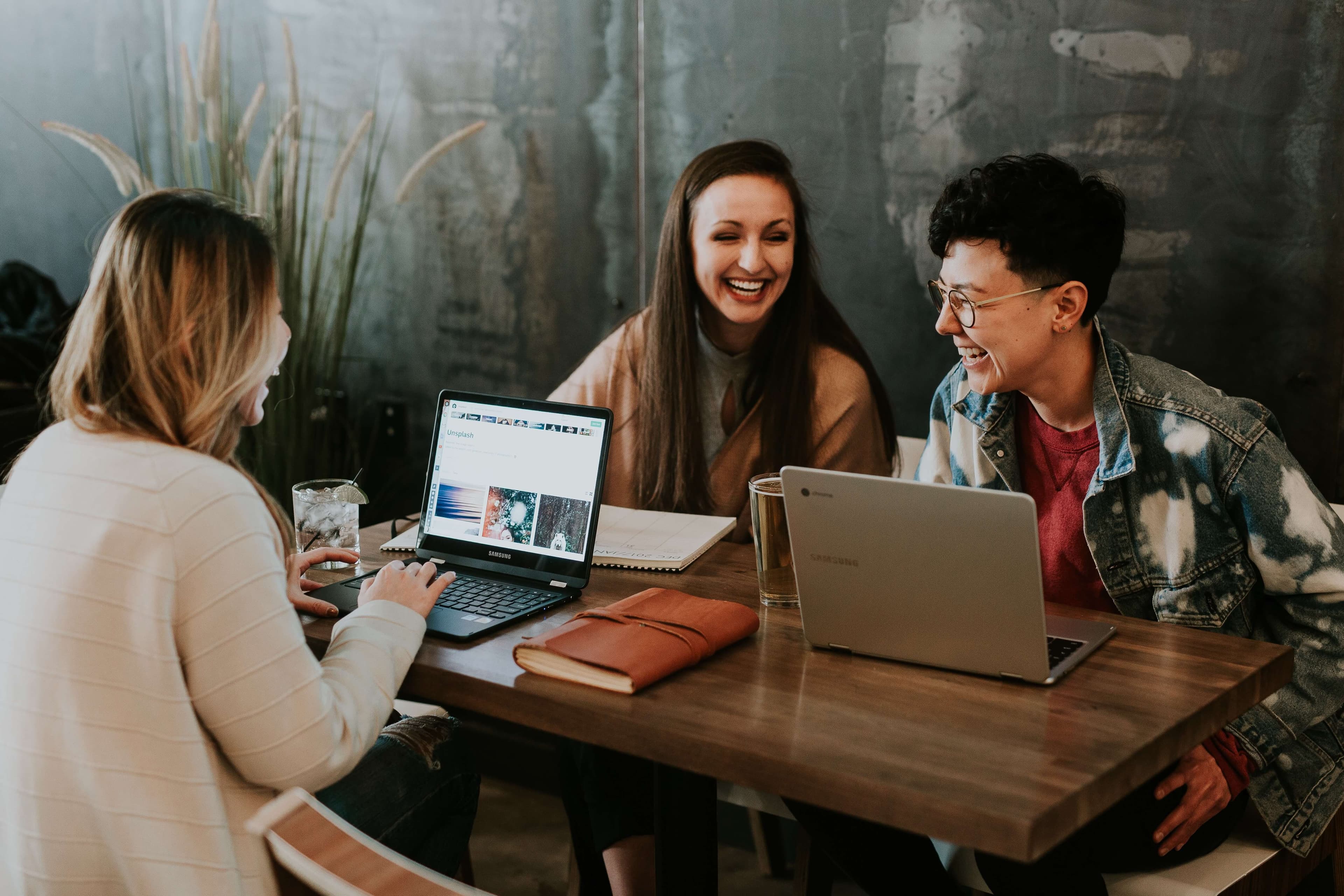 Three people sitting and laughing at their workplace { w: 600, h: 300 }